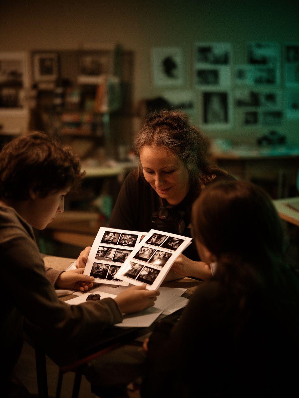 Instructor reviewing contact sheets beside a student in a warm studio critique session